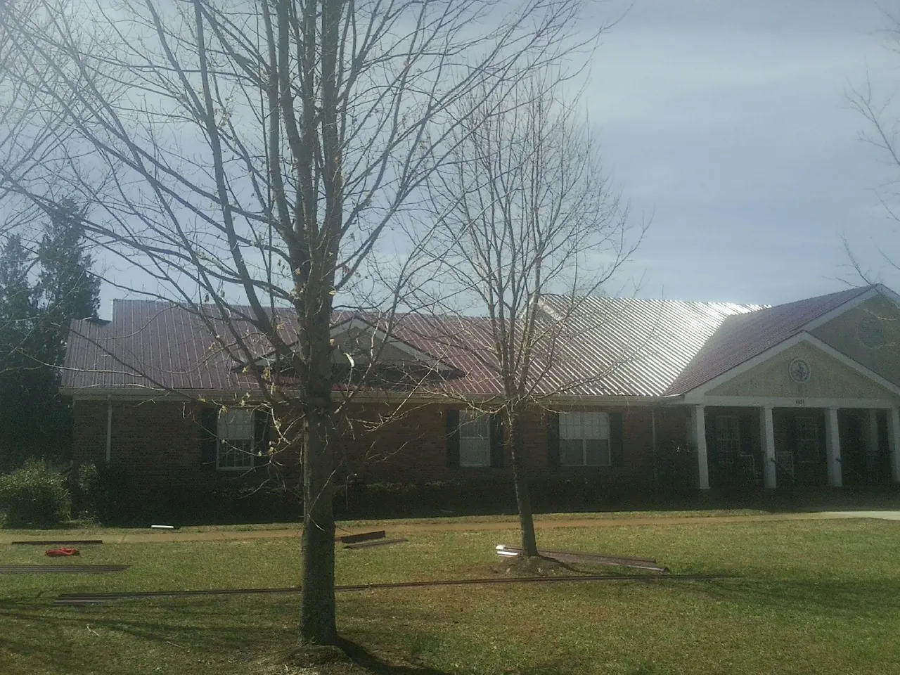 Red metal roof on a brick building seen from the front lawn in Fernley