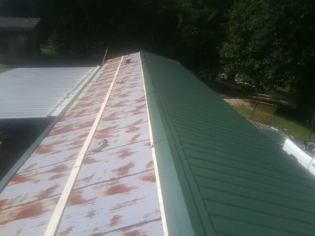 Old rusted panels beside newly installed green metal roofing — Wind Damage Roof Repair by Roofing Brothers in Fernley