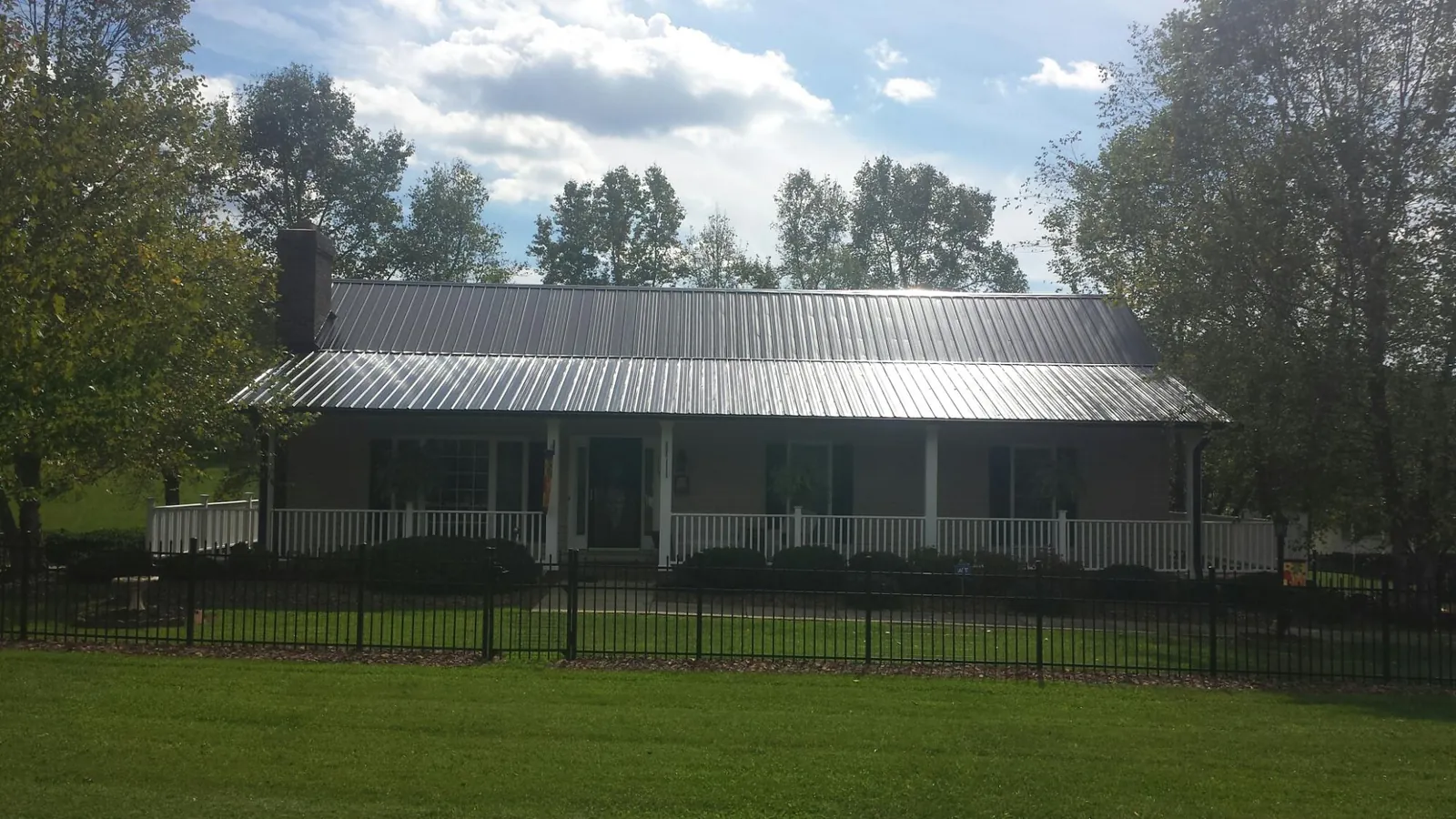 Gray metal roof on a brick ranch with a full width front porch — Gutter Guard Installation work by our crew in Fernley