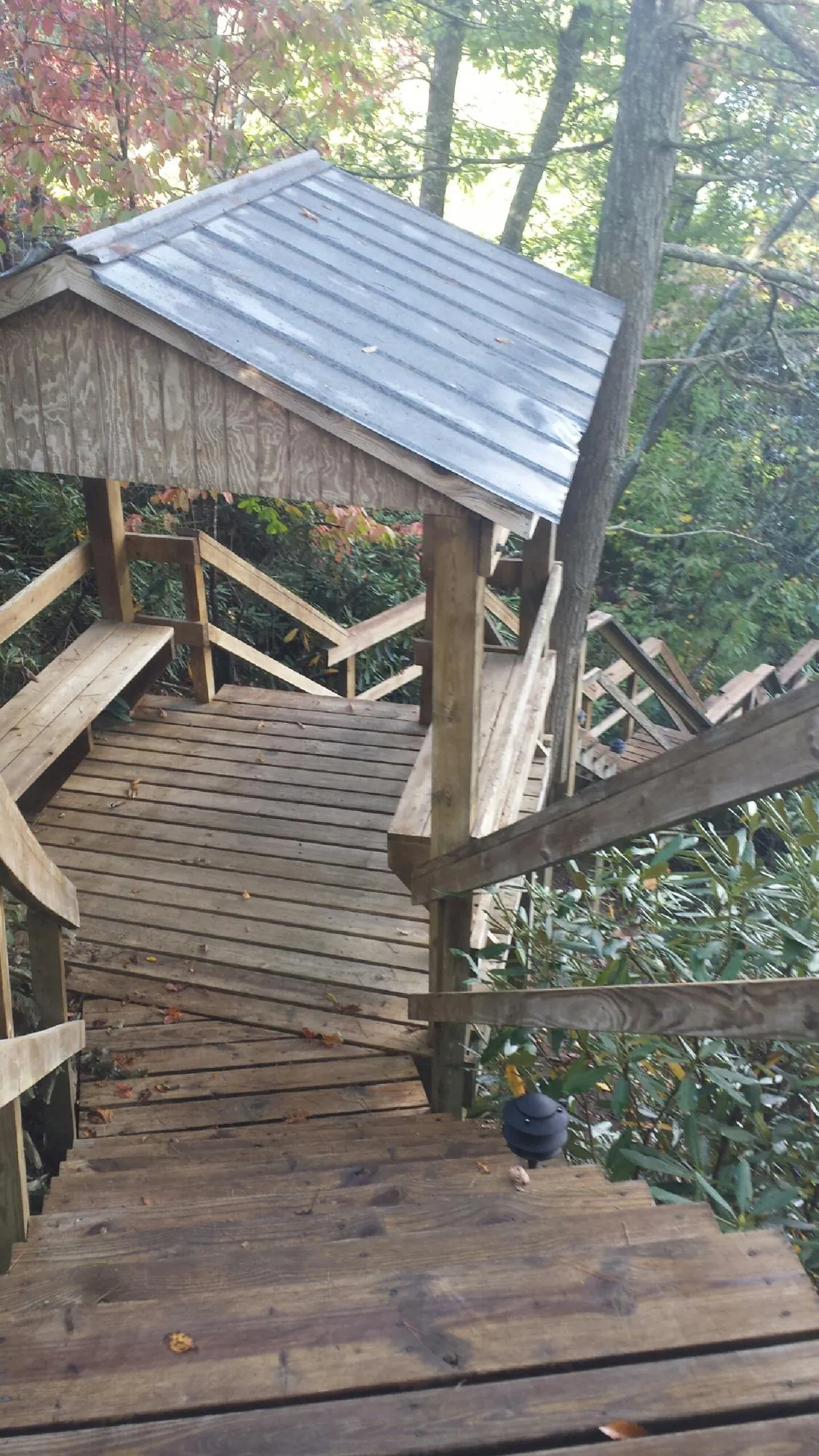 Metal roofed shelter over wooden steps on a wooded walkway — Skylight Repair & Installation work by our crew in Fernley