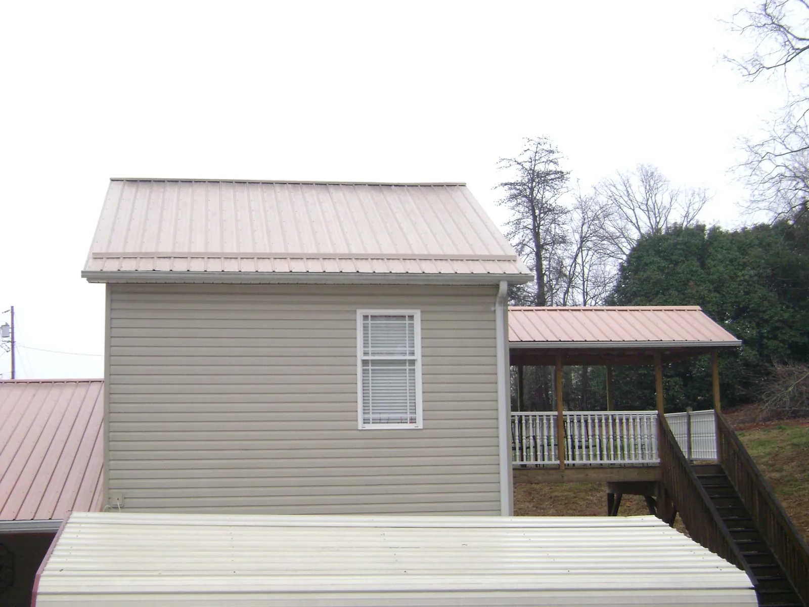 Tan metal roofs on a two story addition and attached porch, from a Roof Replacement job in Fernley